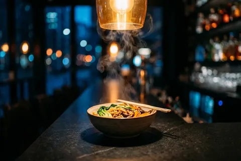 Bowl of wok noodles on a dark counter at night